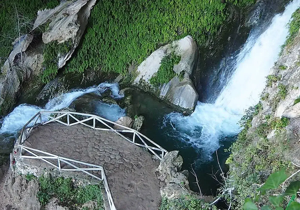 Vista aérea de la cueva del agua Tiscar, con cascadas cayendo y un mirador de madera.