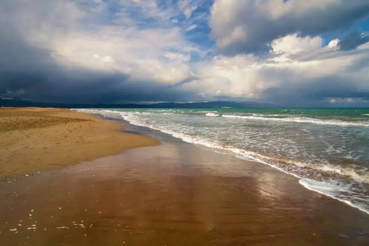 Arena dorada y mar turquesa bajo un cielo dramático. Un lugar idílico para desconectar, como si fueran playas cerca de Zaragoza.