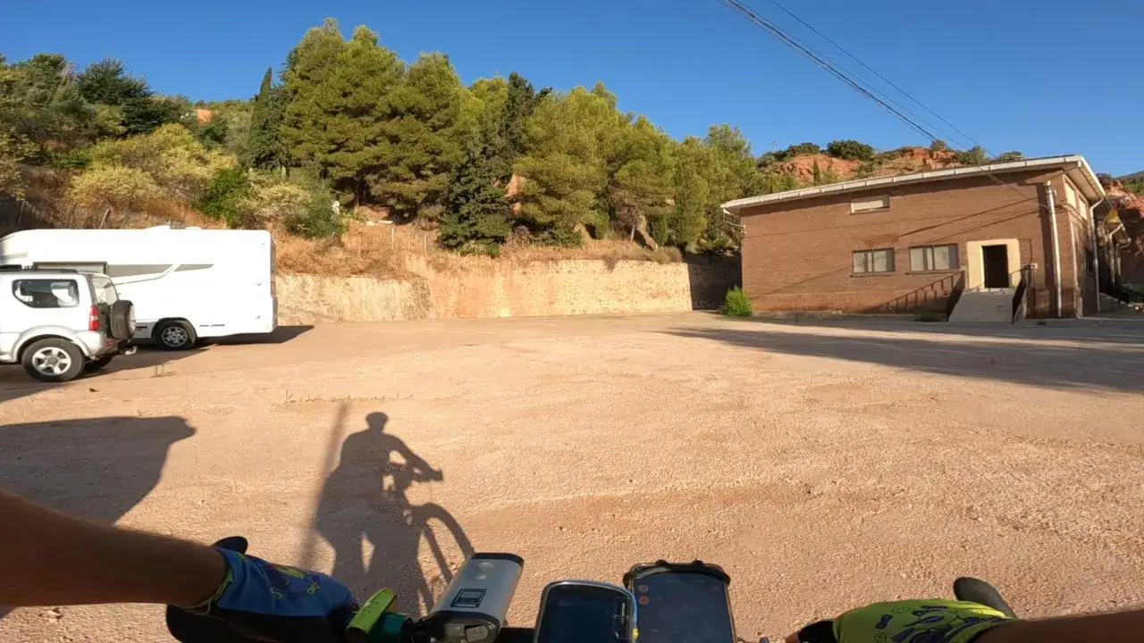 Sombra de ciclista en un camino de tierra, con una caravana y un edificio de ladrillo al fondo. ¿Bogarra como llegar?