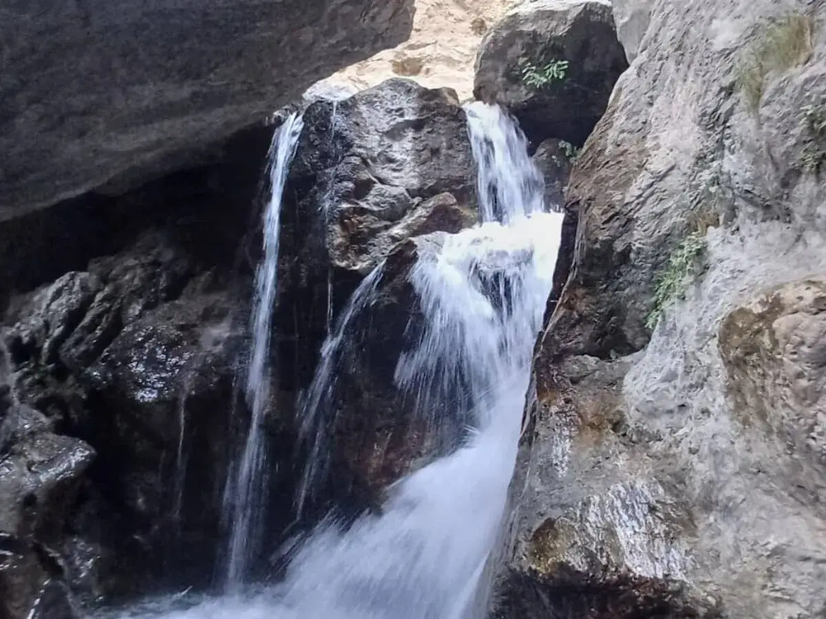 Cascada en la ruta de los bolos, agua cayendo entre rocas musgosas.