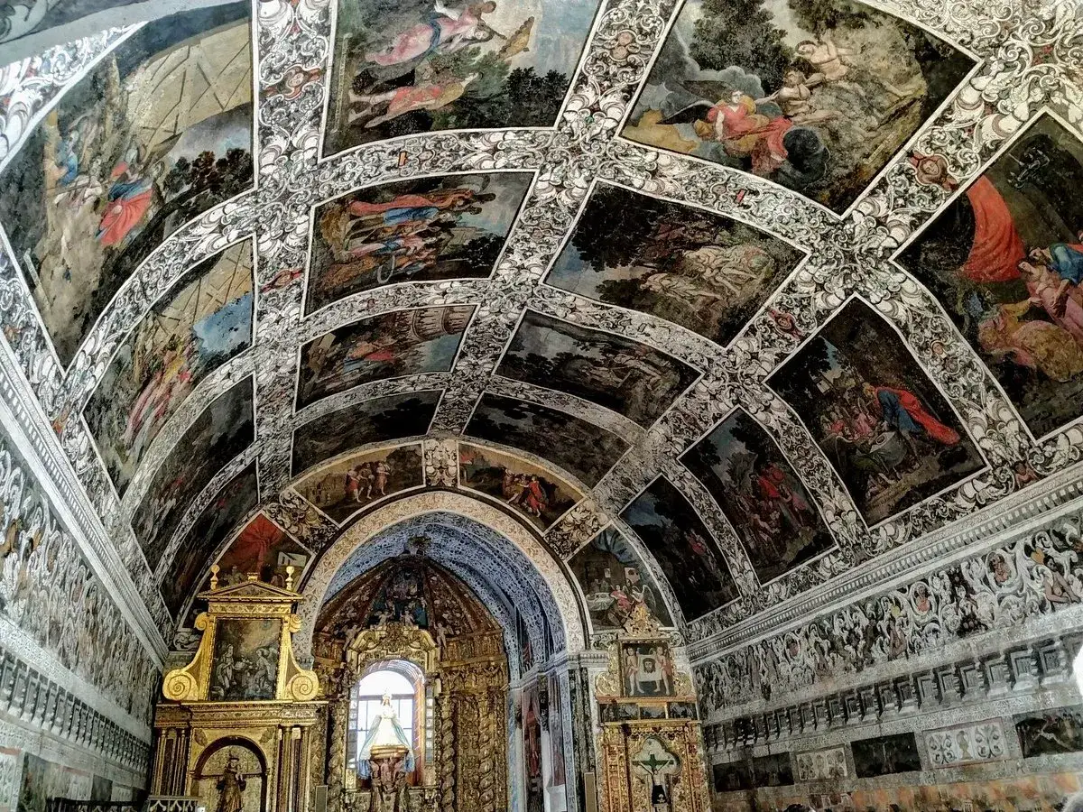 Interior de la ermita Virgen del Ara, con bóveda y paredes cubiertas de pinturas murales históricas.