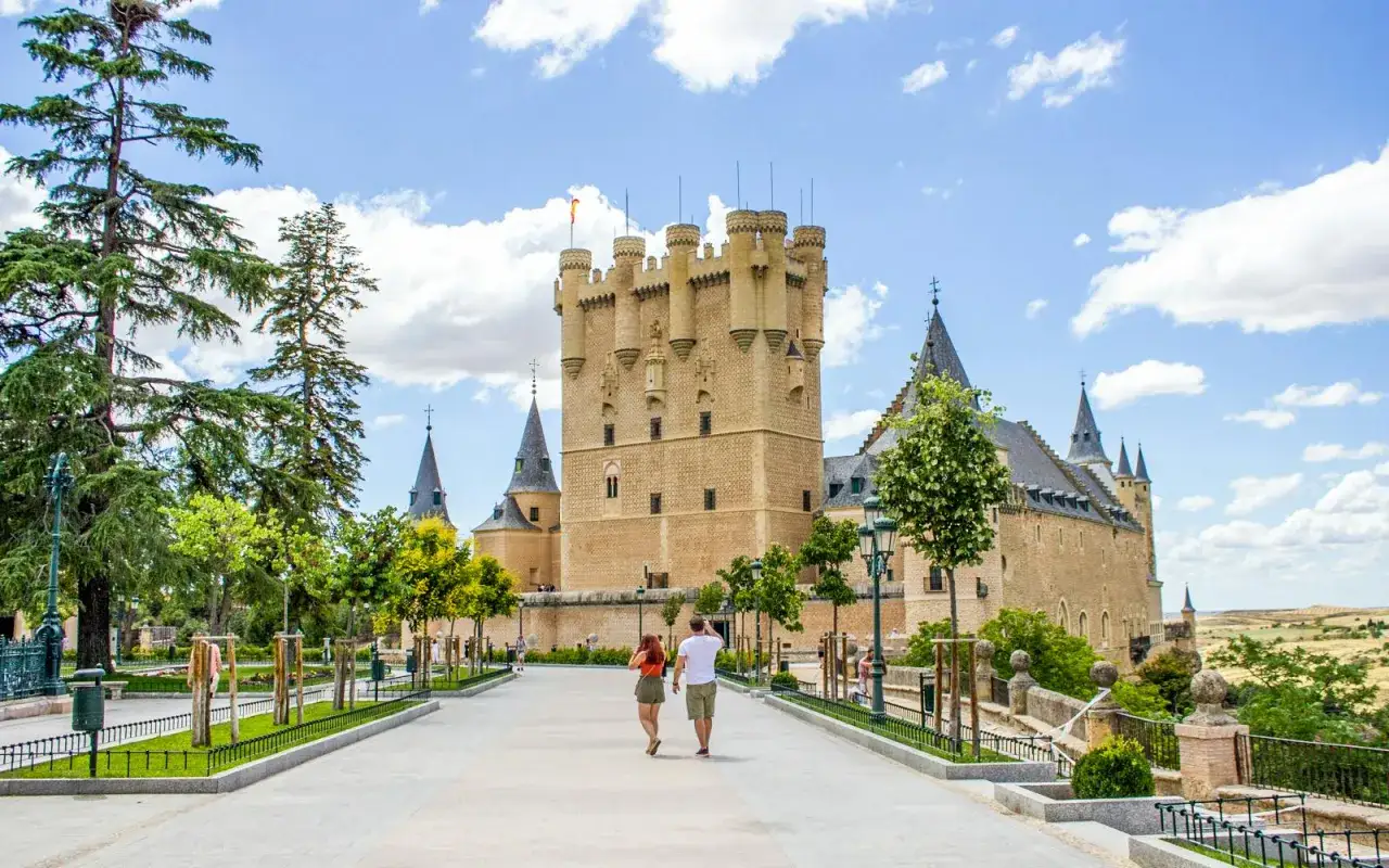 Pareja camina hacia el Alcázar de Segovia, un castillo de cuento. Descubre segovia como llegar y maravíllate.