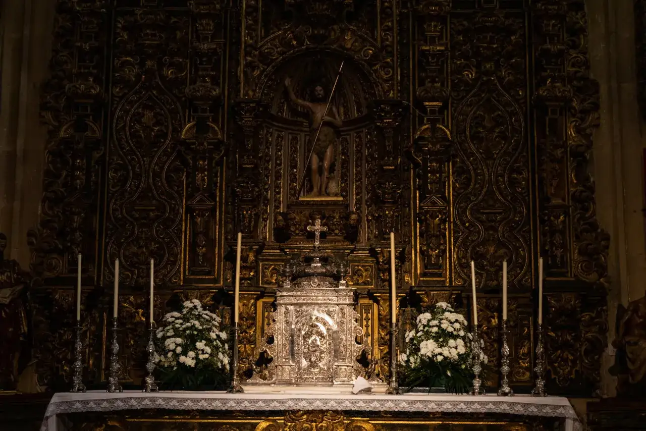 Retablo dorado con figura central de San Juan Bautista, un ostensorio plateado y flores blancas. Una joya barroca, la capilla Sixtina extreme&ntilde;a.