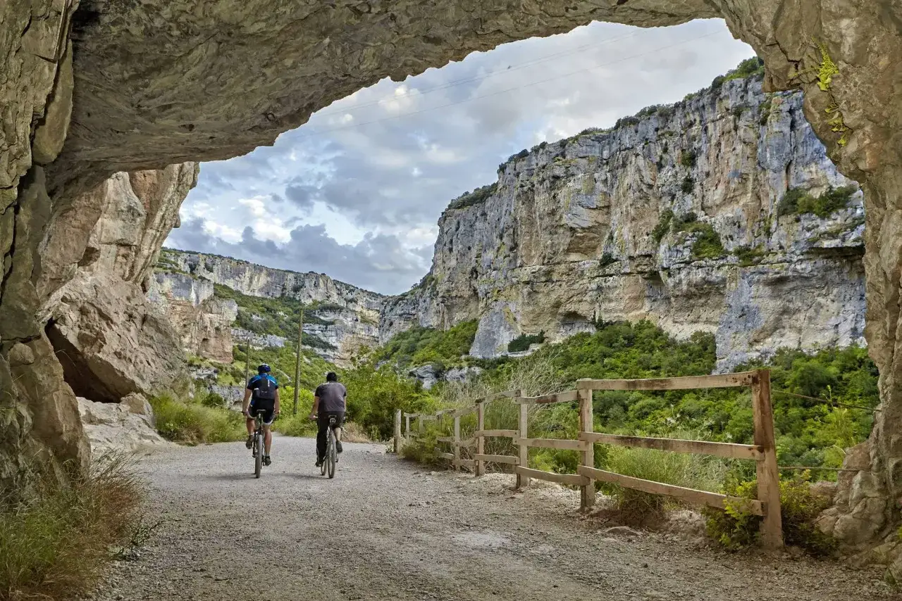 Dos ciclistas exploran la Foz de Lumbier ruta, un impresionante ca&ntilde;&oacute;n con paredes rocosas y vegetaci&oacute;n exuberante.
