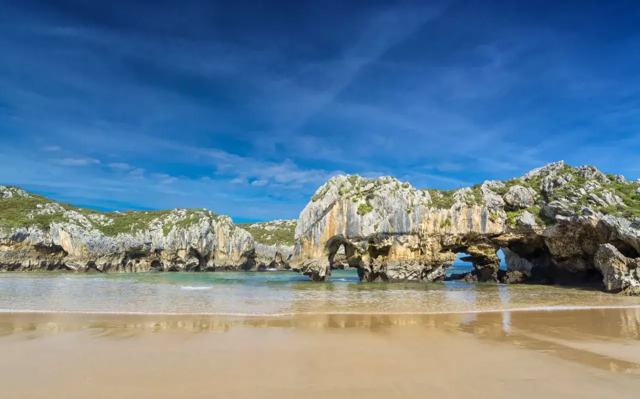 Playa con formaciones rocosas y arcos naturales, un ejemplo de las mejores playas de Asturias.