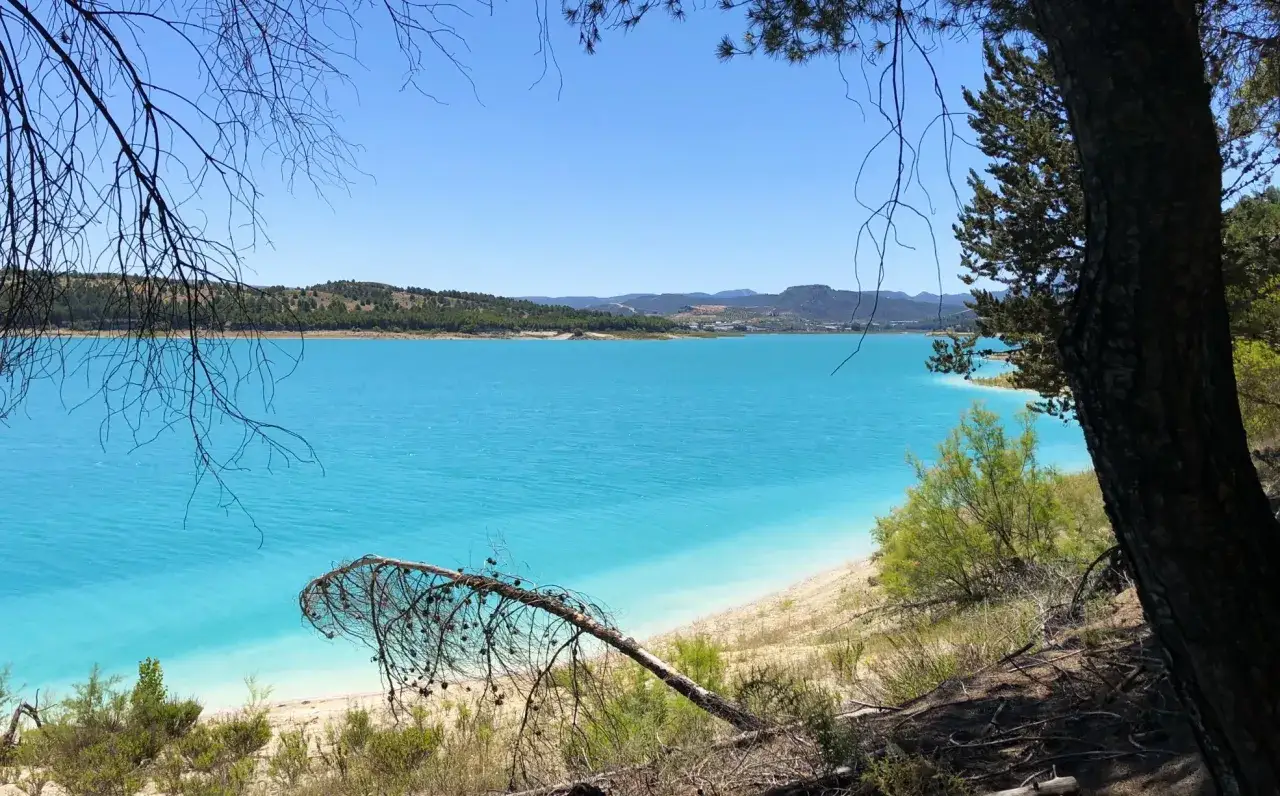 El pantano de los Bermejales, con sus aguas turquesas y la vegetación que lo rodea, ofrece una vista espectacular.
