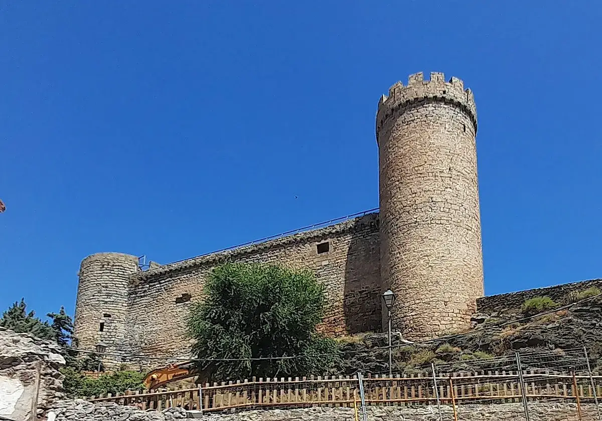 El imponente castillo de Cornago se alza bajo un cielo azul intenso, con sus torres de piedra y murallas contando historias de antaño.
