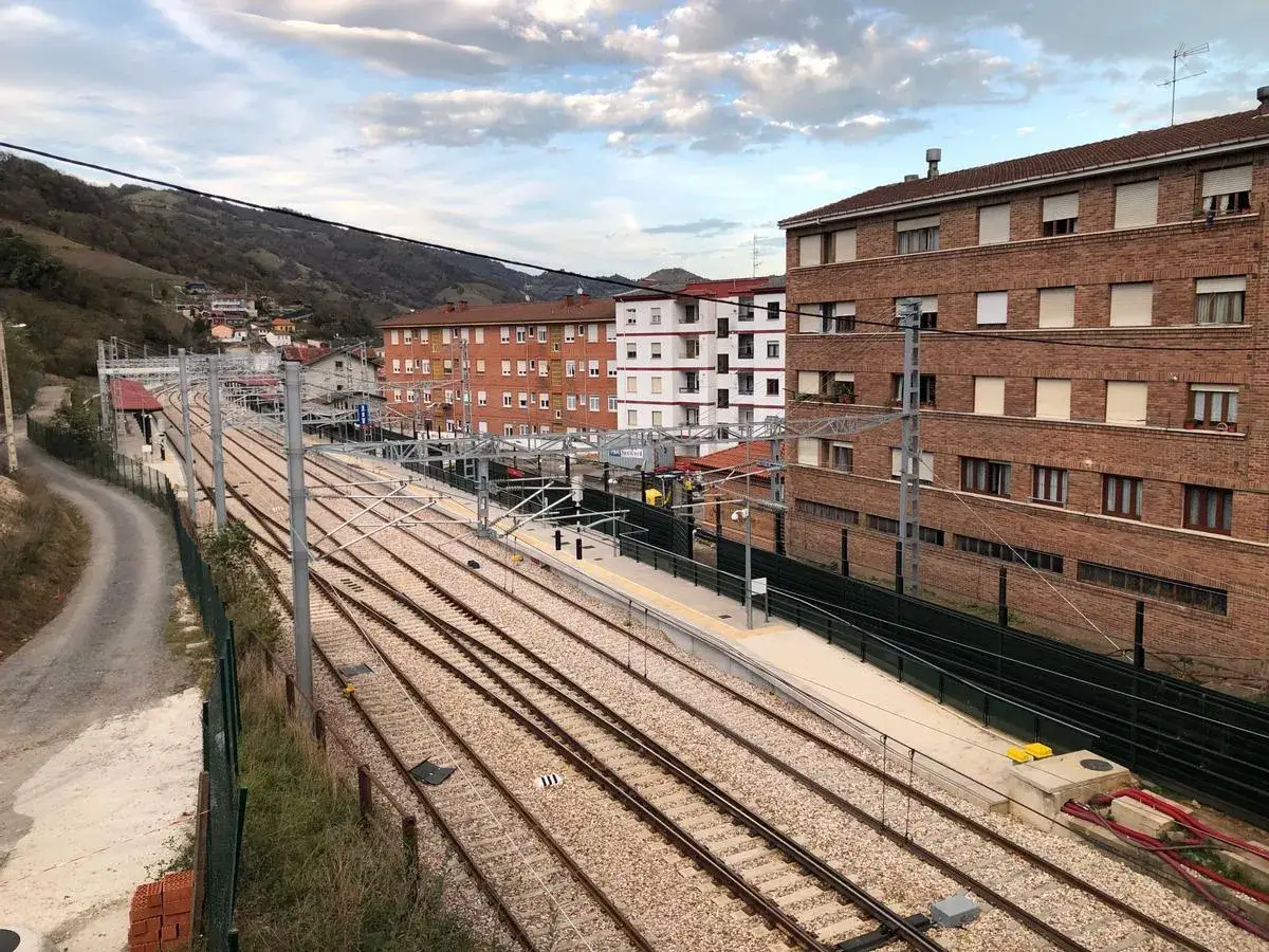 Estación de tren en Pola de Lena. Vistas de las vías, edificios de ladrillo y casas en la ladera.