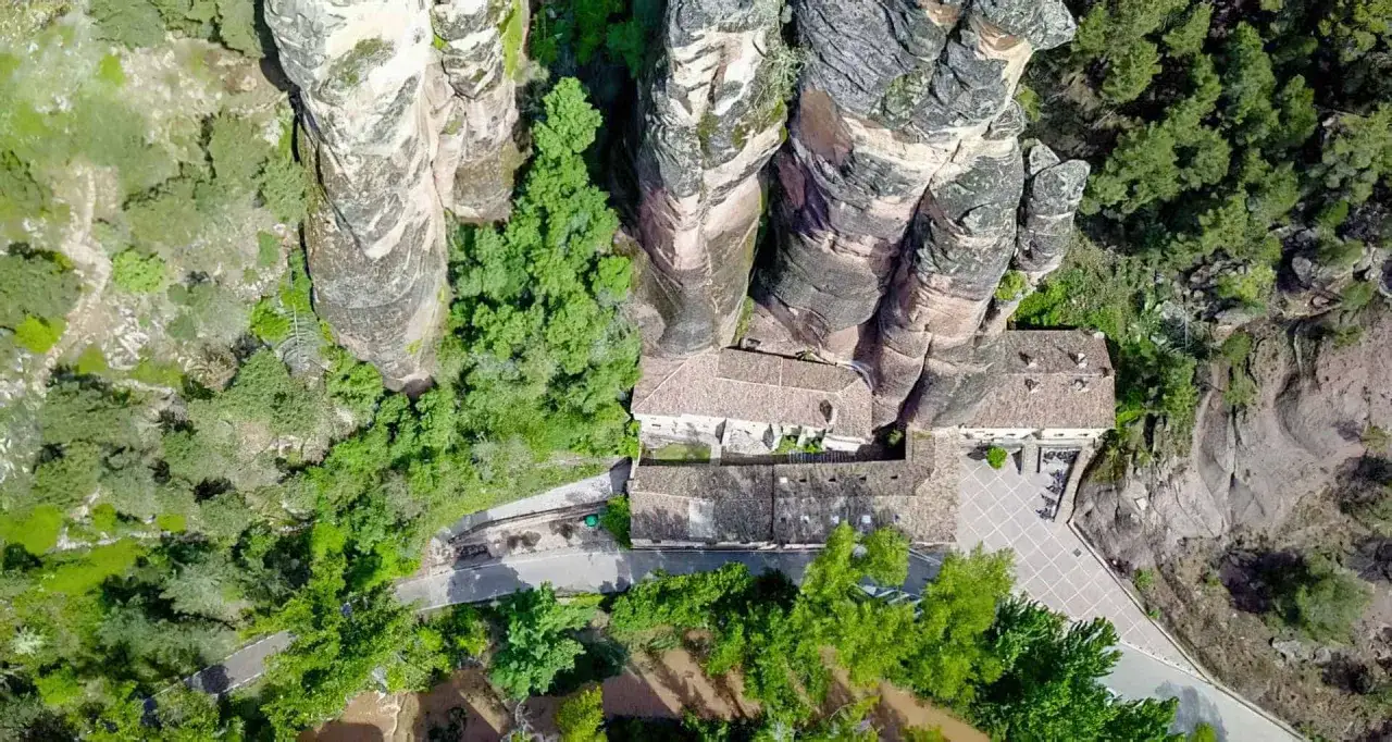 Edificio hist&oacute;rico en la ruta del barranco de la Hoz, rodeado de imponentes rocas y vegetaci&oacute;n.