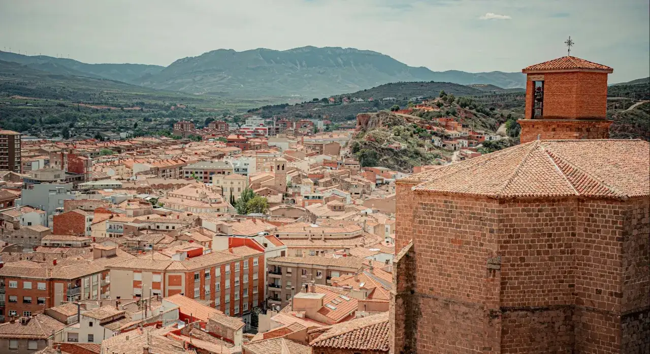 Vista panorámica de Arnedo, con tejados naranjas y montañas al fondo. Descubre cómo llegar a este pintoresco pueblo.