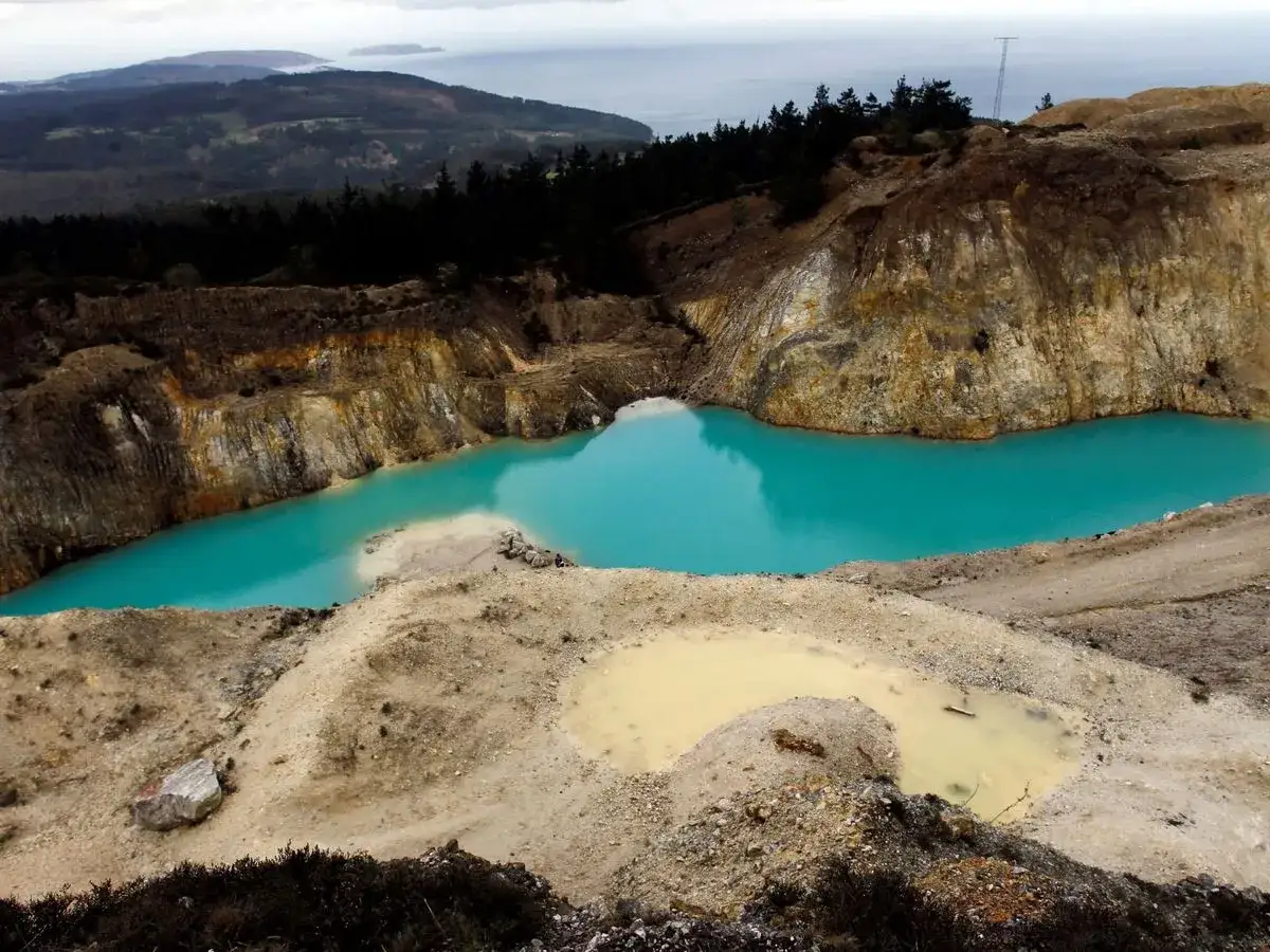 Laguna turquesa en el monte Neme Carballo, un paisaje minero con aguas de color intenso y formaciones rocosas.